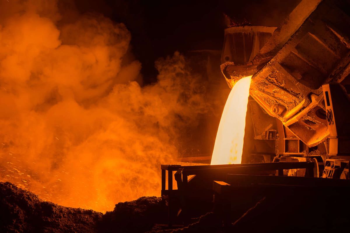 Molten metal pouring from a ladle in a smoky foundry