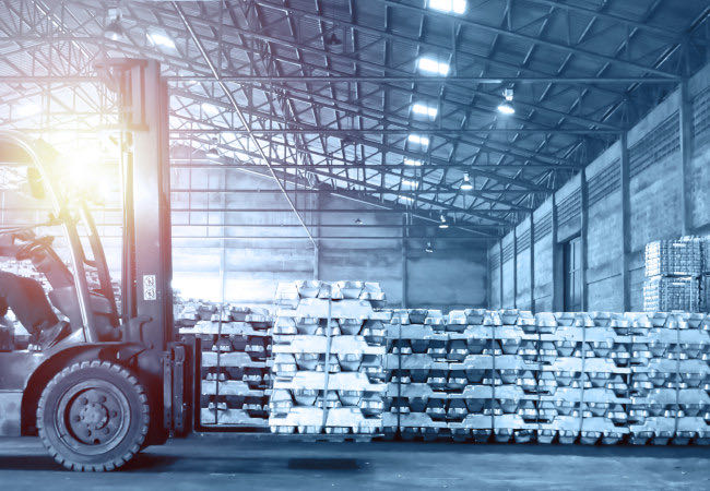 Forklift beside stacked metal ingots in a warehouse