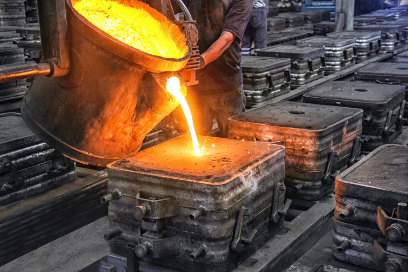 Worker pouring molten metal from a ladle into ingot molds